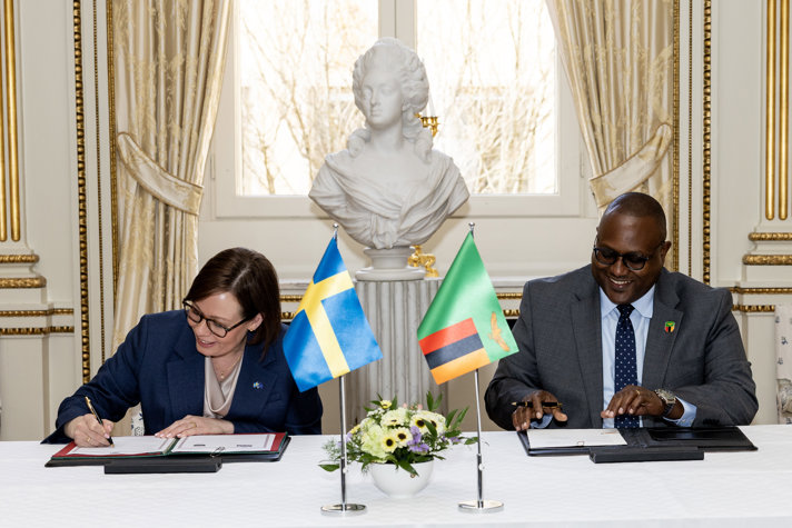 Maria Malmer Stenergard och Mulambo Haimbe undertecknar avtal sittandes vid bord.