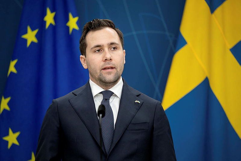 Benjamin Dousa står framför svensk flagga och EU-flagga på pressträff.