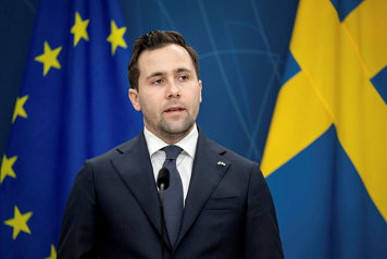 Benjamin Dousa står framför svensk flagga och EU-flagga på pressträff.